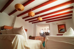 Ein Zimmer mit zwei Betten, Holzbalken an der Decke und hängenden Gewebeleuchten.