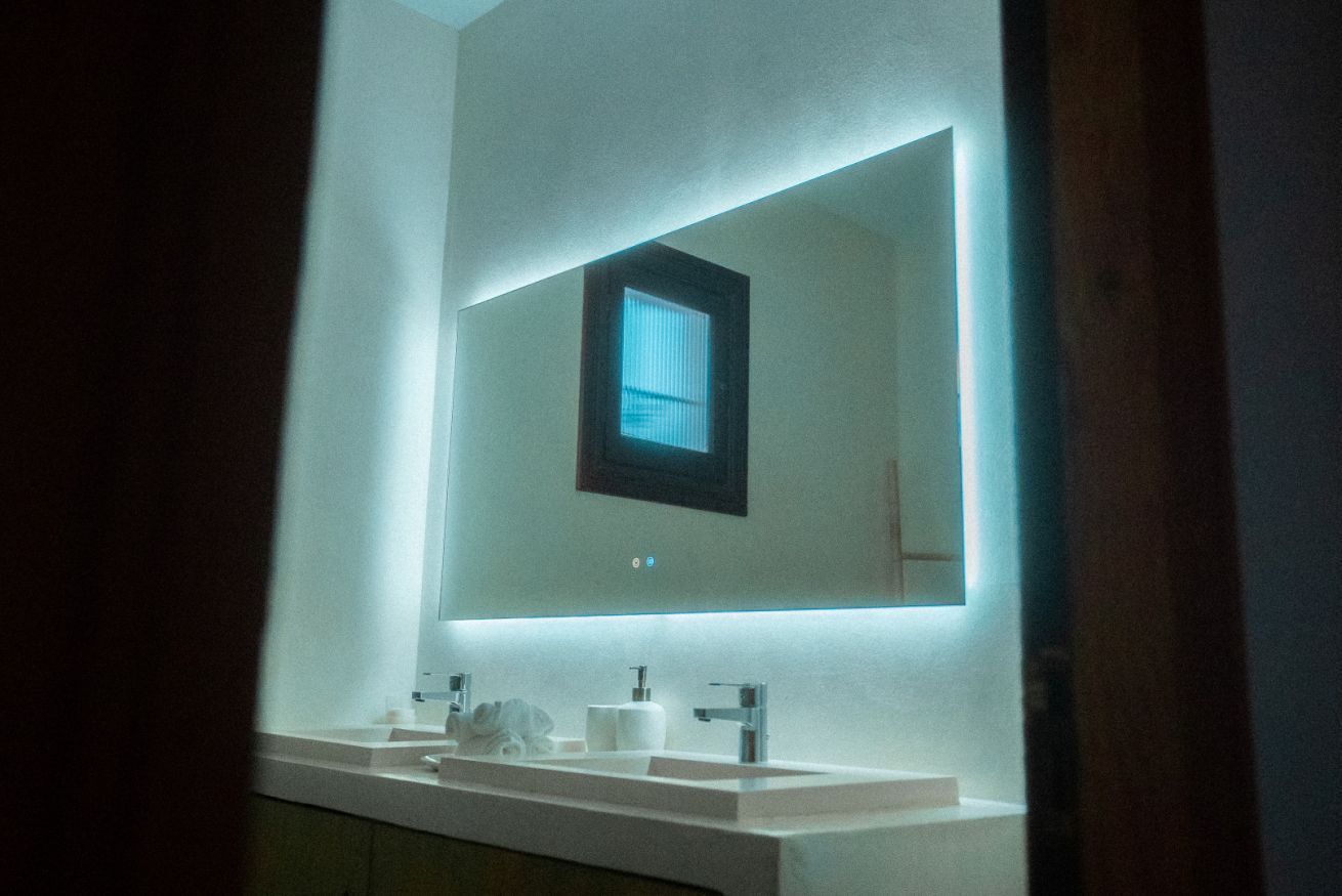 Un baño con un espejo grande, un lavabo y una ventana.
