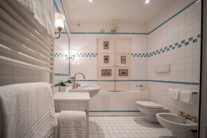Un baño con lavamanos, inodoro, bidé y un perchero para toallas.
