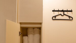A closet with hanging space and shelves, containing folded towels. - Train Pod at one-north (Singapore)