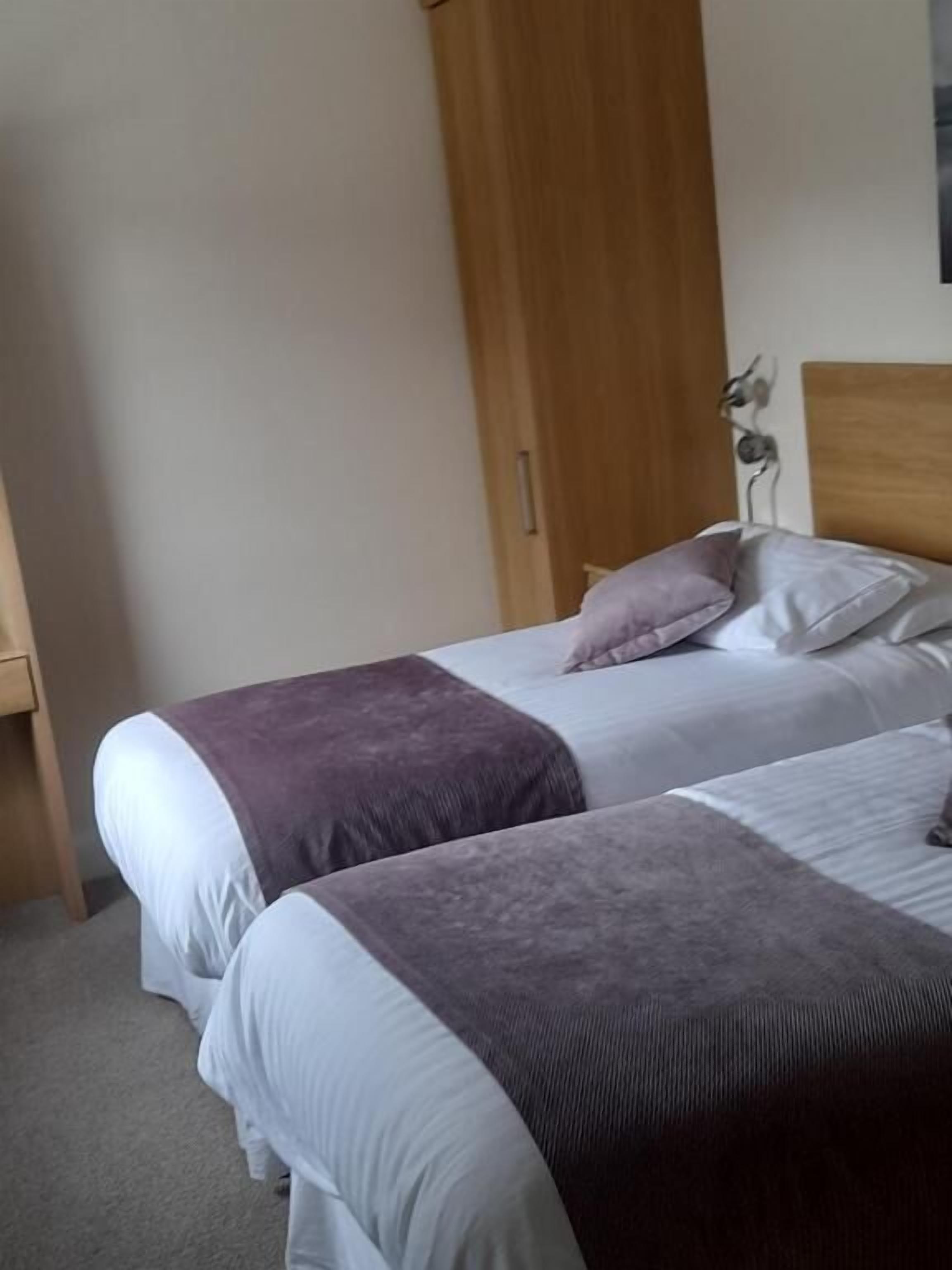 A bedroom with two beds, a wooden wardrobe, and a small decorative item on the wall.