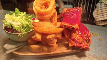 En træfad med salat, løgringe, pommes frites og en kødret.
