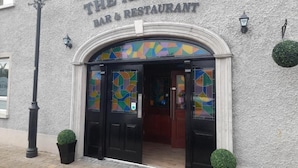 El bar y restaurante Armada, con fachada texturizada, puertas de entrada negras y un ventanal de vidrio emplomado colorido.