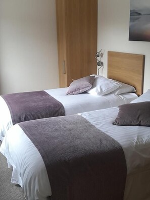 Two beds with headboards, a wooden wardrobe, and a wall-mounted artwork. - The Armada Bar And Restaurant (Armoy)