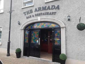 The Armada Bar & Restaurant with a textured facade, black-framed entrance, and decorative glass panels. - The Armada Bar And Restaurant (Armoy)