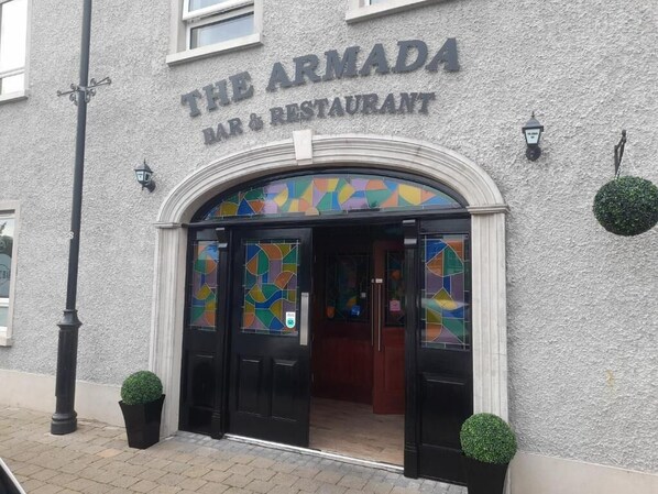 The Armada Bar & Restaurant with a textured facade, black-framed entrance, and decorative glass panels. - The Armada Bar And Restaurant (Armoy)