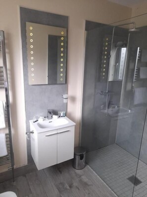 A modern bathroom with a glass shower enclosure, a vanity with a mirror, and a sink. - The Armada Bar And Restaurant (Armoy)