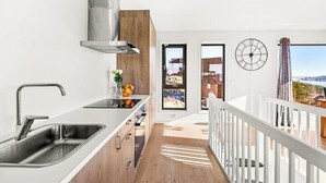 Eine moderne Küche mit Spüle aus Edelstahl, Holzschränken und Blick ins Freie.