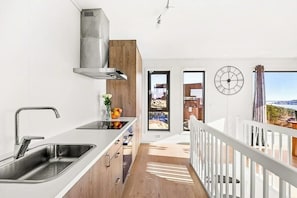 Eine moderne Küche mit Spüle aus Edelstahl, Holzschränken und Blick ins Freie.