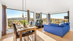 Ein modernes Wohnzimmer mit Essbereich, großen Fenstern und Blick ins Grüne.