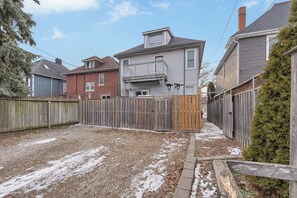A residential backyard with a wooden fence, a gravel driveway, and houses in the background. - Olde Walkerville Wonder! (Windsor)