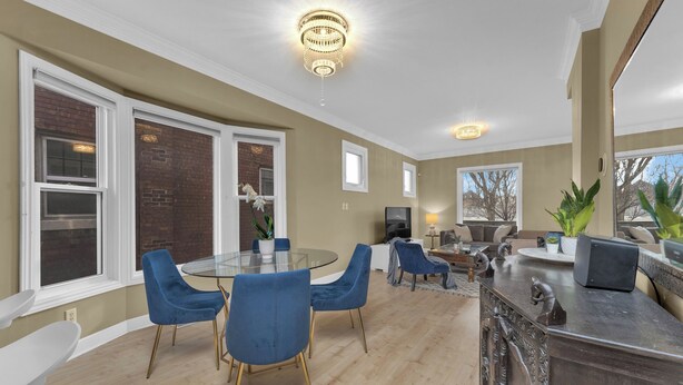 A modern kitchen with a round glass table, blue chairs, and a decorative bar counter. - Olde Walkerville Wonder! (Windsor)