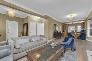 Un salon avec un canapé beige, une table basse en verre et un fauteuil bleu.