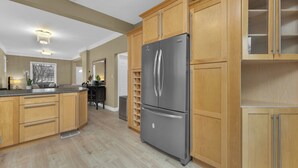 A kitchen with wooden cabinets, a stainless steel refrigerator, and a built-in oven. - Olde Walkerville Wonder! (Windsor)