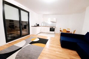 A modern apartment with a living area, a kitchen, and a sliding glass door leading to a balcony. - Elegancia Rueil, 20 min de Paris La Défense, quartier recherché, Lac (Rueil-Malmaison)