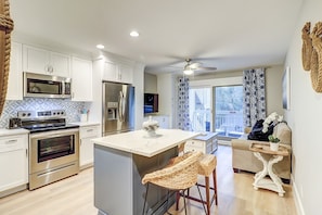 A modern kitchen with stainless steel appliances, a large island, and a view to the outside. - Steps To The Beach + Oceanfront Pool! (Hilton Head Island)