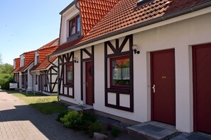 Eine Reihe traditioneller Fachwerkhäuser mit roten Türen und einem gepflasterten Weg.