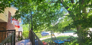 Un barrio residencial con una casa de ladrillo, un columpio y un trampolín.