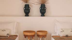 A room with a bed, two small wooden stools, a wall-mounted shelf with two decorative vases, and a thatched ceiling. - Riad le5 - Luxirious private Riad - All Inclusive (Marrakech)