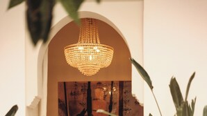 An arched doorway leading to a seating area with a chandelier, a painting, and potted plants. - Riad le5 - Luxirious private Riad - All Inclusive (Marrakech)