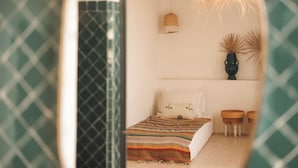A bedroom with a bed, a hanging light, a shelf with decorative items, and a window with a patterned curtain. - Riad le5 - Luxirious private Riad - All Inclusive (Marrakech)