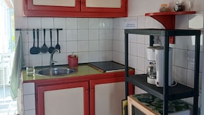 Cozinha com armários vermelhos, pia, cafeteira e micro-ondas em uma prateleira.
