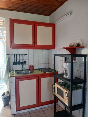 A kitchen with red cabinets, a sink, a coffee maker, and a microwave on a shelf. - L'ARUM 97280 (Le Vauclin)