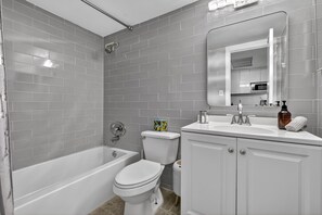 A bathroom with a bathtub, toilet, and sink, all in white. - Stylish Ocean view/front Studio + Pool (Sunny Isles Beach)