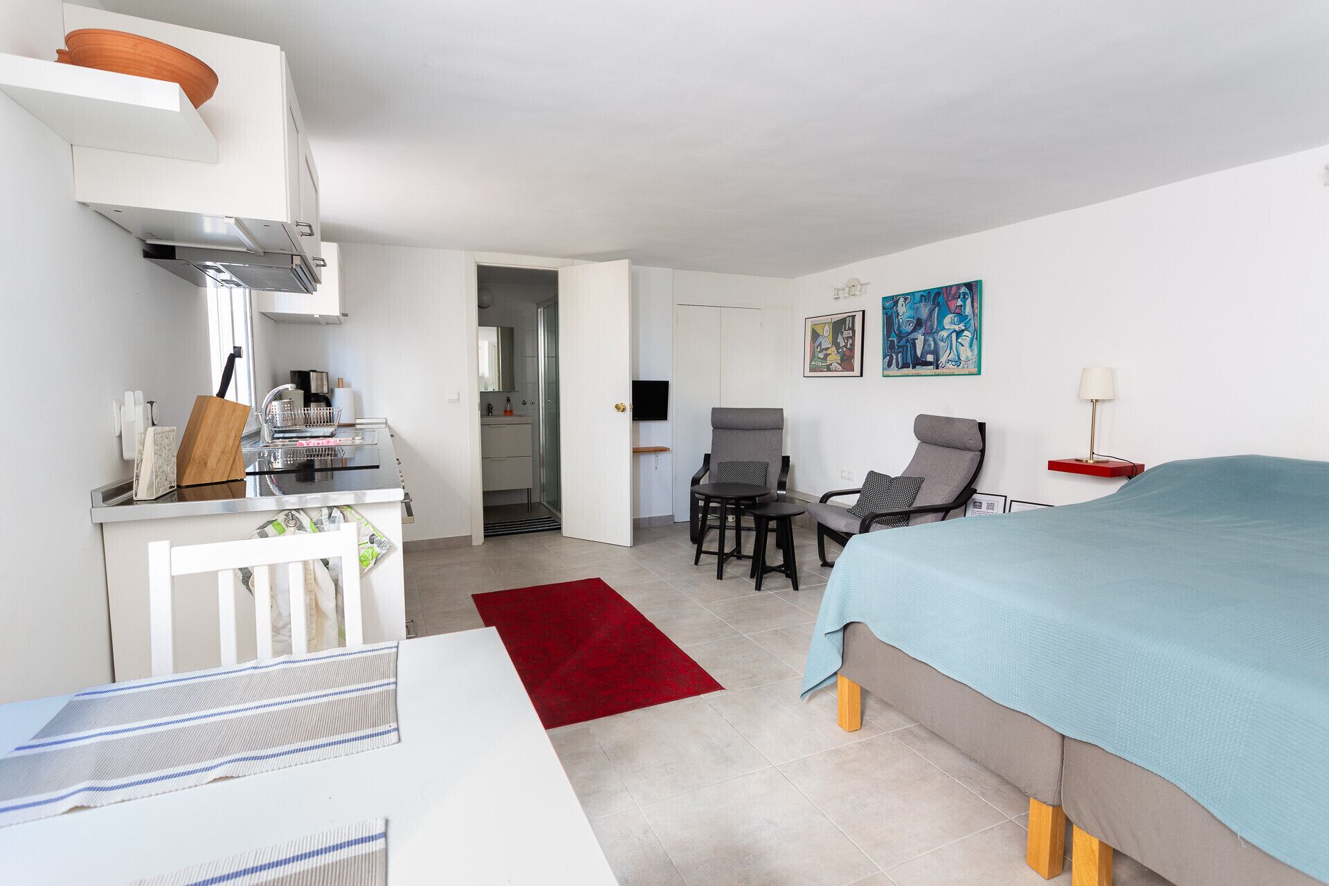 Et moderne hotelværelse med tekøkken, spiseplads, brusebad og seng.