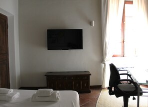 A hotel room with a bed, a flat-screen TV mounted on the wall, a wooden dresser, and a chair. - BQA San Crisogono Apartments Rome-Trastevere (Roma)