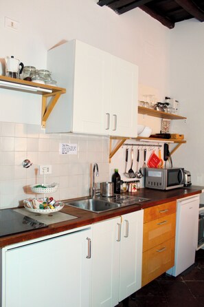 A kitchen with white cabinets, a wooden countertop, a sink, and various kitchen utensils. - BQA San Crisogono Apartments Rome-Trastevere (Roma)