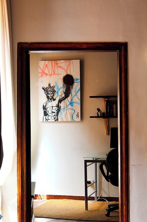 A room with a framed artwork on the wall, a desk with a chair, and a bookshelf. - BQA San Crisogono Apartments Rome-Trastevere (Roma)