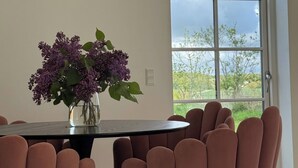 A dining area with a table, chairs, and a vase of flowers. - Estate in Calm Nature (Soro)