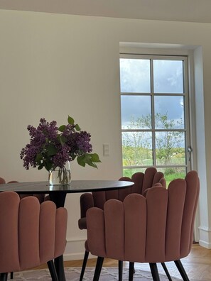 Un comedor con una mesa, sillas y un jarrón de flores.