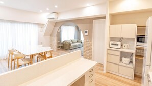 A modern kitchen with a dining area, a built-in microwave, and a small refrigerator. - Now Available - Spacious House in Yokohama/Chinatown, Grand Yokohama Stay (Yokohamashi Nakaku Yamashitacho)