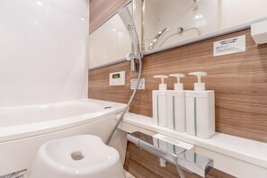 A modern bathroom with a bathtub, a toilet, and a vanity with soap dispensers.