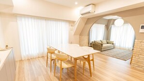 A modern living room with a dining area, featuring a wooden table and chairs, a sofa, and a stone fireplace. - Now Available - Spacious House in Yokohama/Chinatown, Grand Yokohama Stay (Yokohamashi Nakaku Yamashitacho)