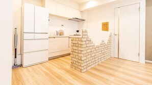 A modern kitchen with white cabinets, a built-in brick accent wall, and a wooden floor. - Now Available - Spacious House in Yokohama/Chinatown, Grand Yokohama Stay (Yokohamashi Nakaku Yamashitacho)