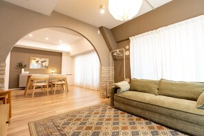 A cozy living room with a sofa, a dining area with a table and chairs, and a kitchen area.
