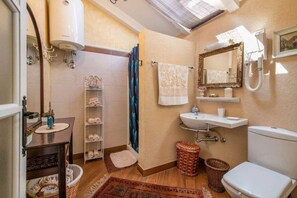 Een badkamer met een douche, wastafel, toilet en een spiegel.