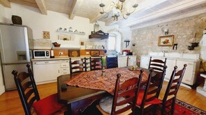 Een eetgedeelte met een tafel, stoelen en een kroonluchter.