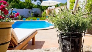 Ein Poolbereich mit Liegestuhl, Topfpflanze und weißem Sonnenschirm.