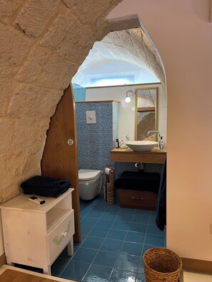 A bathroom with a blue tiled wall, a white sink, and a toilet. - Vrbo Property (Mola di Bari)