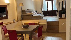 Ein Essbereich mit Tisch und Stühlen, einer Couch, einem Fernseher und einer Treppe, die zu einer oberen Ebene führt.