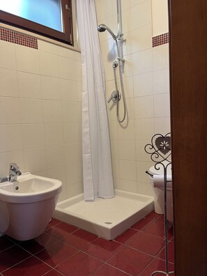 Een badkamer met een douche, een toiletbril en een wastafel.