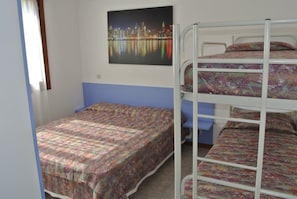 A room with a bunk bed, a single bed, and a cityscape painting on the wall. - Functional Flat Close to the Beach and the Center (Lignano Sabbiadoro)