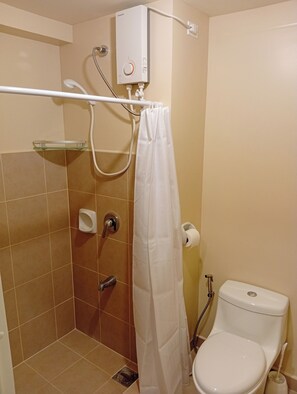 Une salle de bain équipée d’une douche, de toilettes et d’un radiateur fixé au mur.