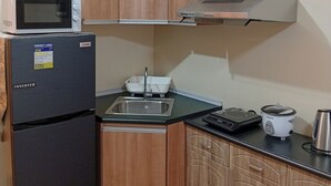 A compact kitchen with a microwave, refrigerator, sink, and a small electric kettle. - Cozy & Convenient | Cebu IT Park Stay (Cebu City)
