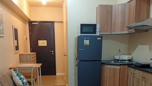 A compact living space with a kitchenette, a sofa with patterned cushions, a small table, and a patterned rug. - Cozy & Convenient | Cebu IT Park Stay (Cebu City)