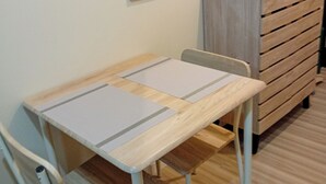 A small, neatly arranged room with a wooden table, two chairs, a mirror, and a wooden dresser. - Cozy & Convenient | Cebu IT Park Stay (Cebu City)